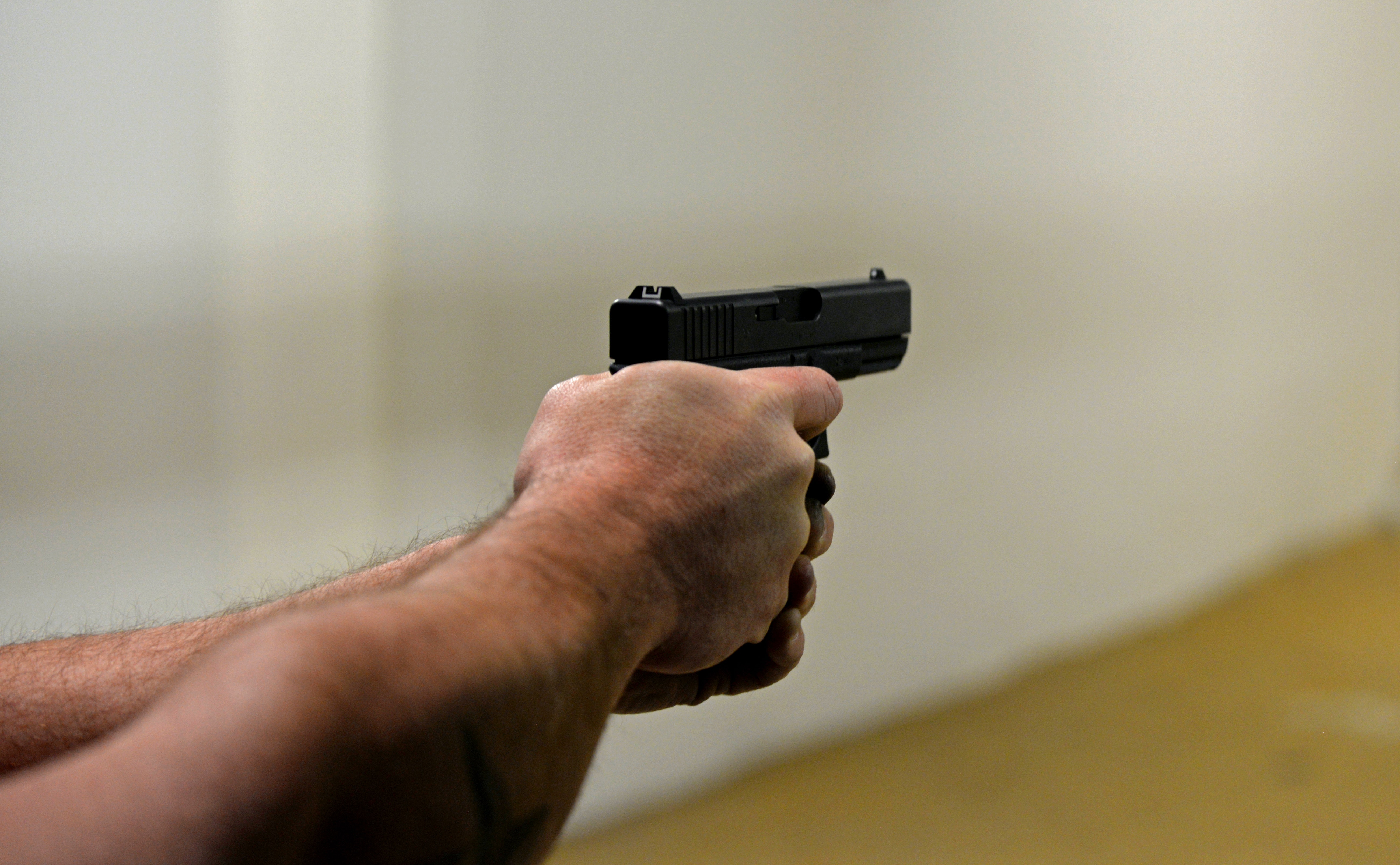 A person aiming a pistol at a firing range