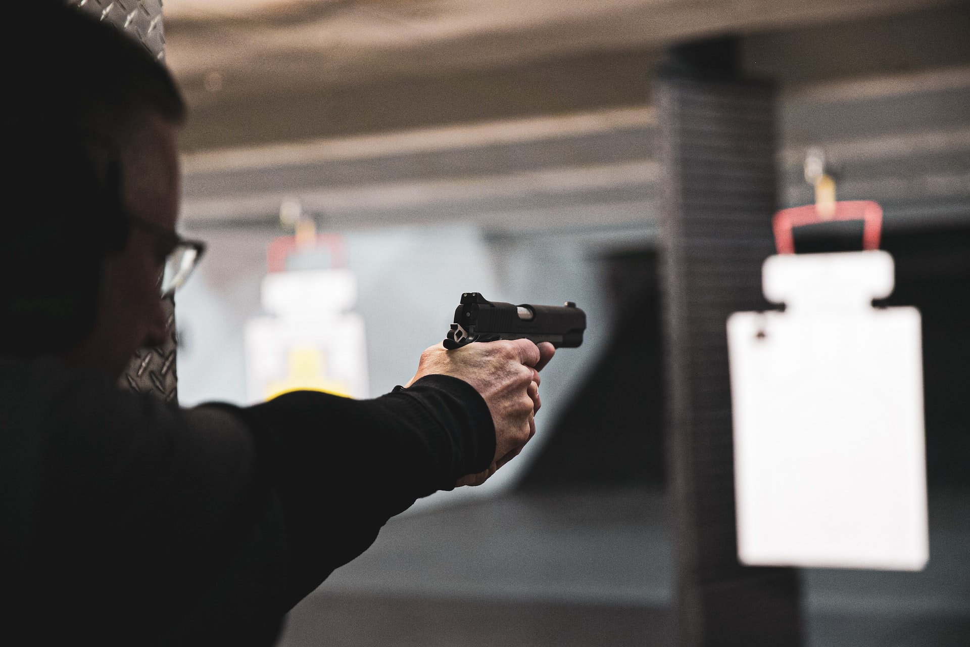 Photo of a man doing indoor target practice with a handgun